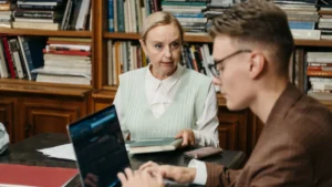 Studentessa e coach a colloquio in una biblioteca