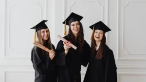 Tre neolaureate in toga e tocco festeggiano con il diploma in mano