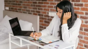 Una giovane studia alla scrivania con il portatile e un quaderno di appunti