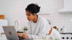 Una studentessa segue una lezione online dal computer di casa, tra libri e appunti